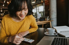 A young woman researches on her phone at a cafe.