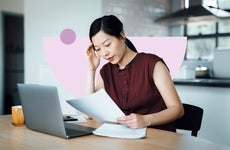 Woman studying a document and working on a laptop