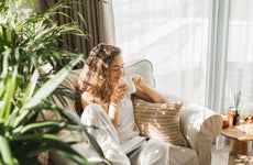 Woman at home reading book and drinking coffee