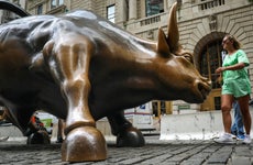 Tourists visit the Wall Street bull statue in the Financial District