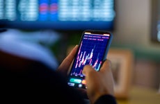 Man looking at currency trading app on his smart phone from his home office